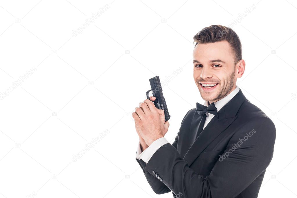 cheerful secret agent in black suit holding gun, isolated on white