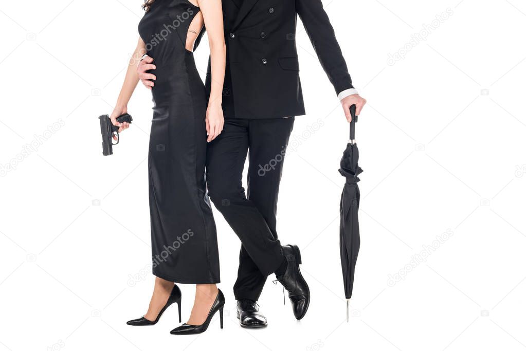 cropped view of couple of killers in black clothes holding gun and umbrella, isolated on white