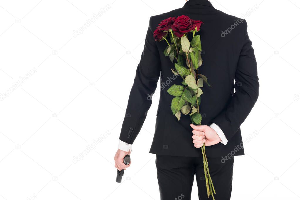 back view of killer in black suit holding handgun and red rose flowers, isolated on white