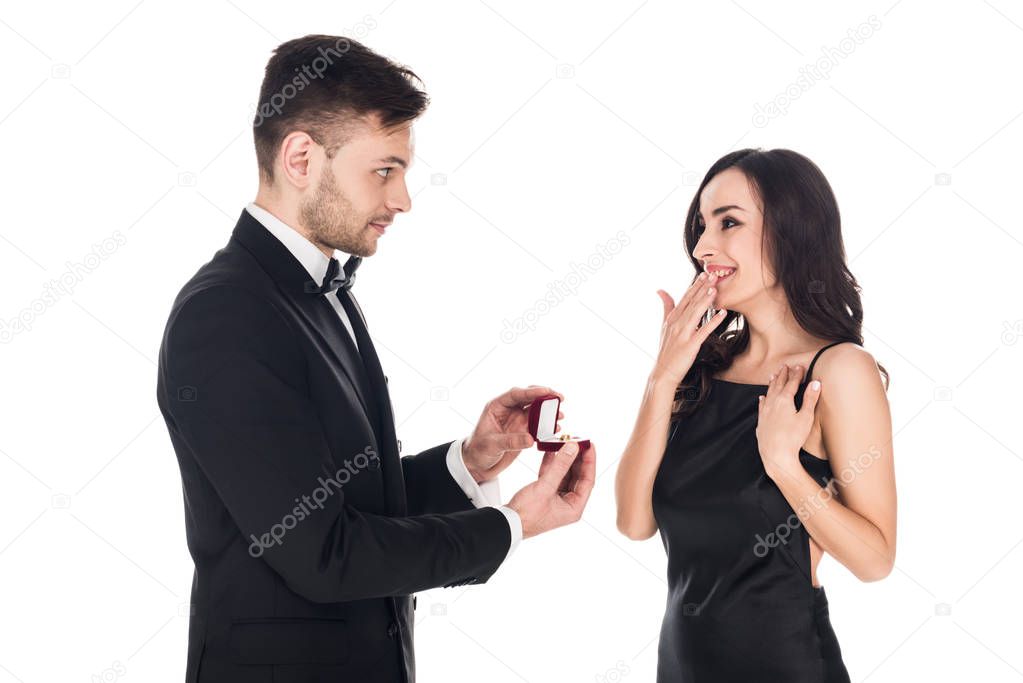 happy boyfriend giving proposal ring in box to surprised girlfriend, isolated on white 