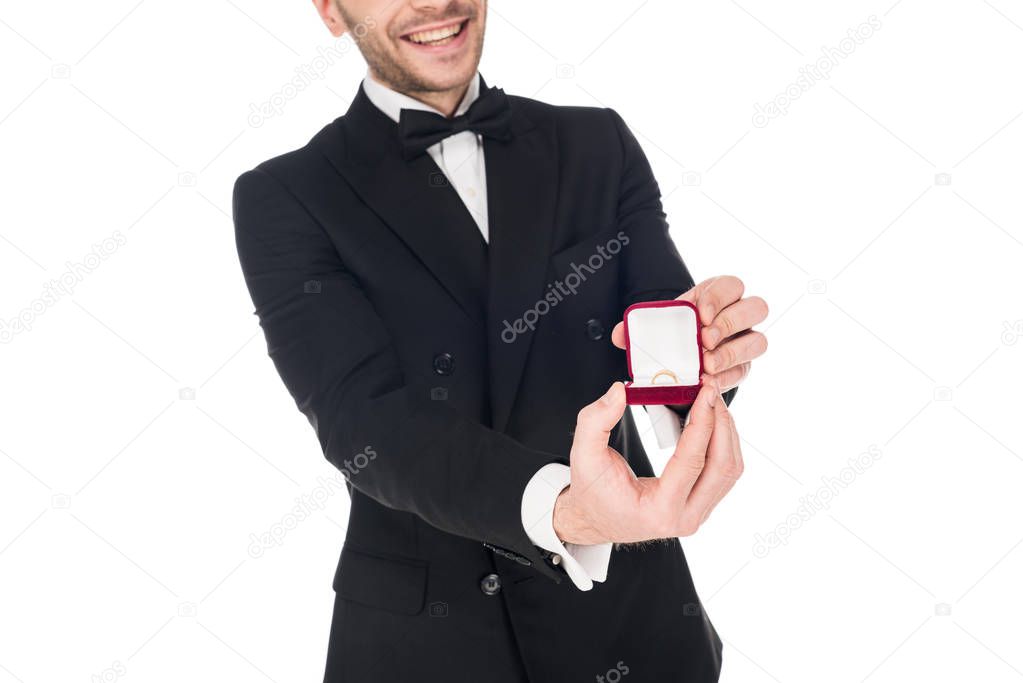cropped view of elegant man in black tuxedo holding proposal ring, isolated on white