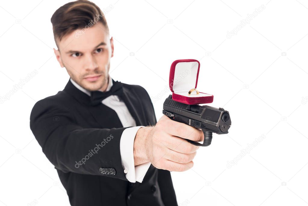 male killer in black suit aiming with gun with proposal ring, isolated on white