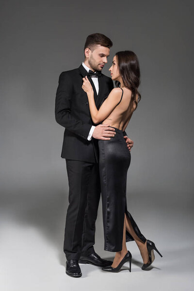 beautiful couple in black clothes hugging on grey