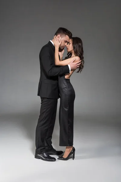 美丽优雅的夫妇在黑色的衣服拥抱在灰色 — 图库照片