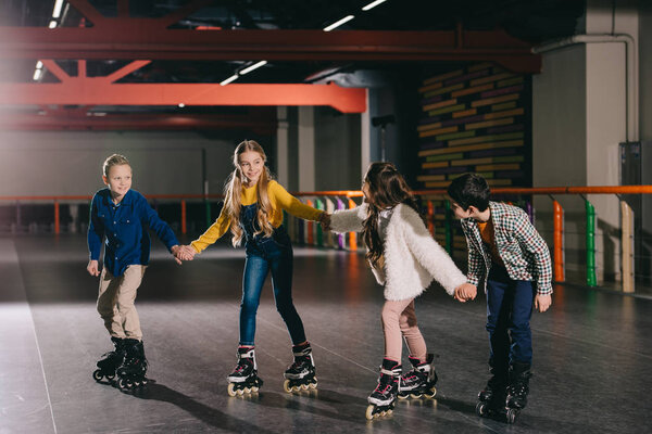 Smiling children in roller skating on roller rink and holding hands