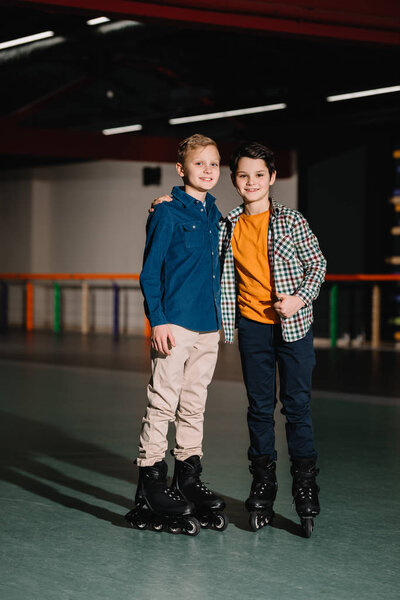 Selective focus of smiling boys in roller skates with one hugging friend