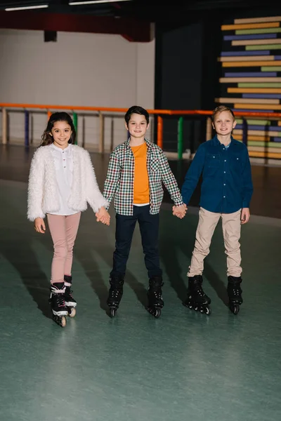 Tres Lindos Niños Sonrientes Patines Pie Con Las Manos Cogidas — Foto de Stock