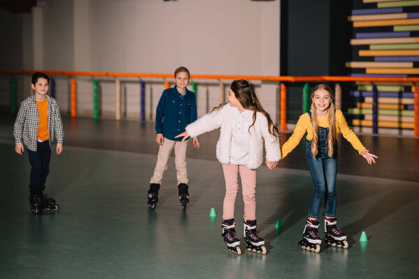 Friends in roller skaters laughing and holding hands 