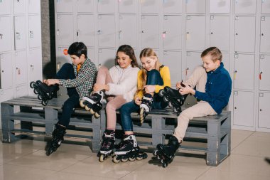 Dört gülümseyen çocuk tekerlekli paten üzerinde koyarak