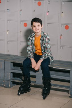 Cute brunette boy in checkered shirt posing in roller skates clipart