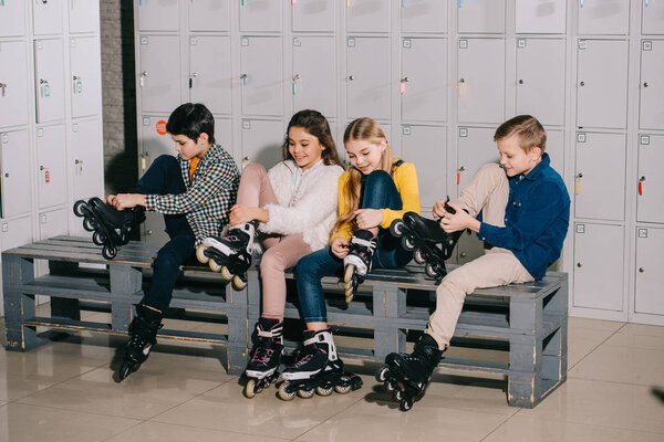 Four smiling kids putting on roller skates