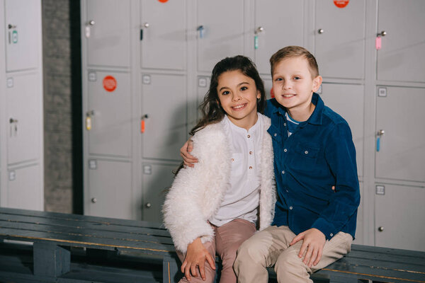 Улыбающийся мальчик обнимает лучшего друга в раздевалке
