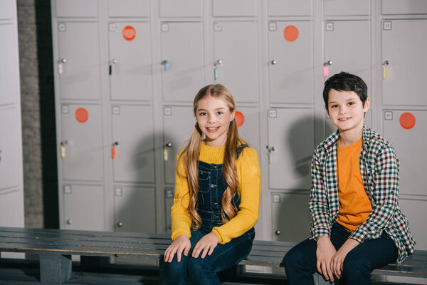 Милые дети сидят в раздевалке с улыбкой
