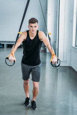 direnç bands ile egzersiz ve spor salonunda kamera bakarak kas yakışıklı genç görünümünü tam uzunlukta 