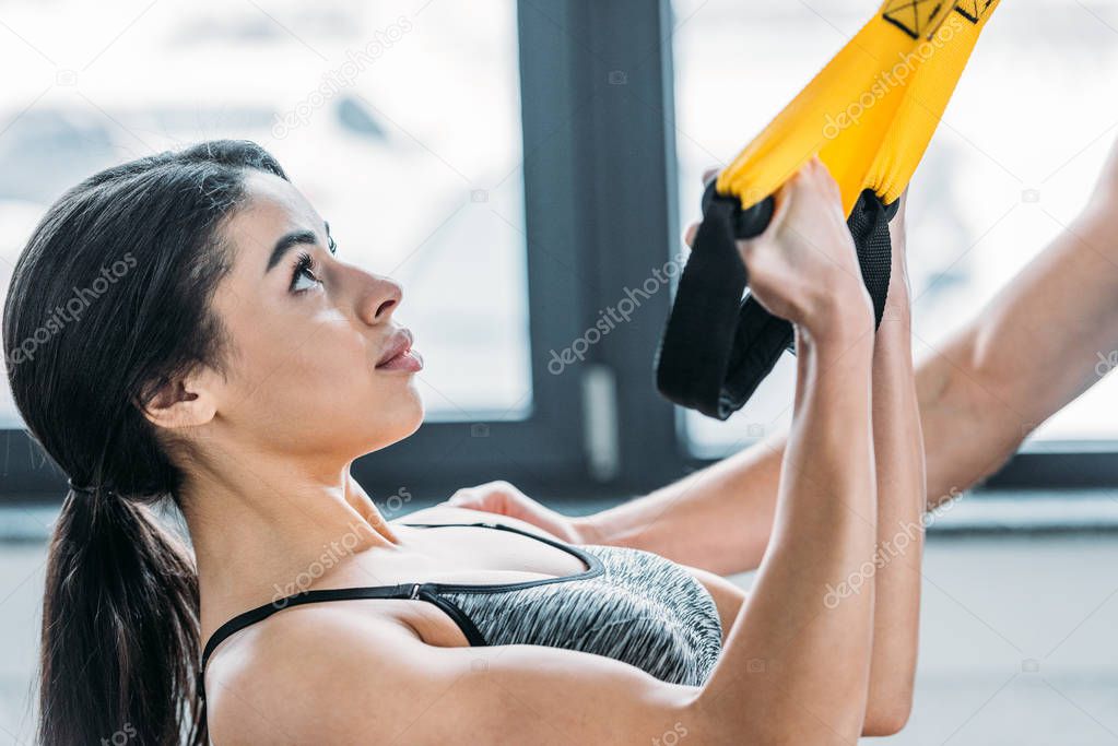 young african american woman training with suspension straps in gym