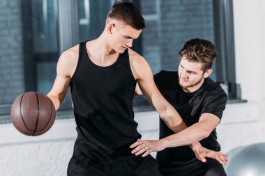 athletic young men in sportswear playing basketball in gym 