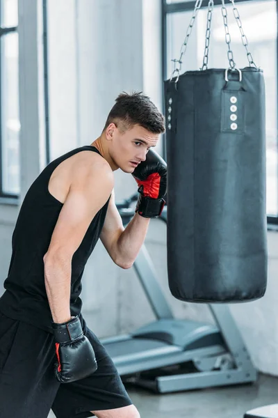 Athletischer Junger Mann Boxhandschuhen Beim Training Mit Boxsack Fitnessstudio — Stockfoto