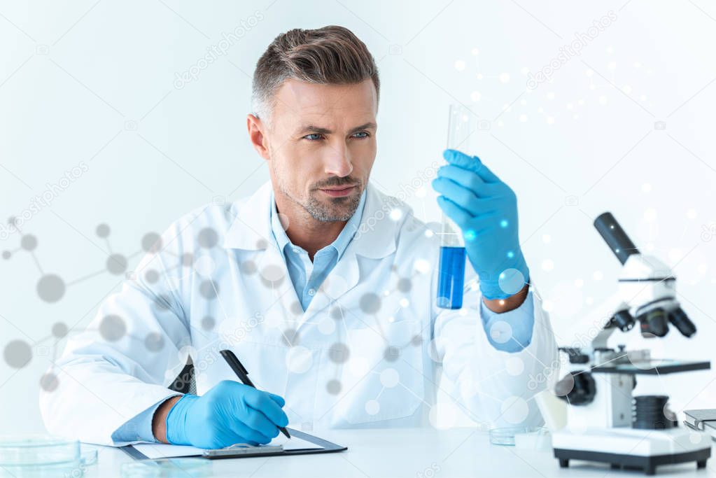 handsome scientist looking at test tube with blue reagent 