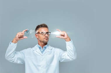 handsome scientist in glasses holding medical interface isolated on grey, artificial intelligence concept clipart