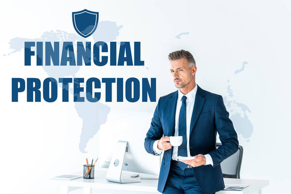 handsome businessman holding cup of coffee and looking at camera isolated on white with map and "financial protection" lettering 