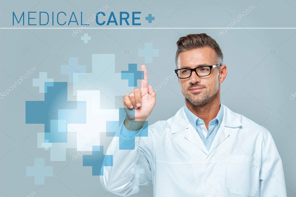 Handsome scientist in white coat and glasses touching medical care interface in air isolated on grey, artificial intelligence concept