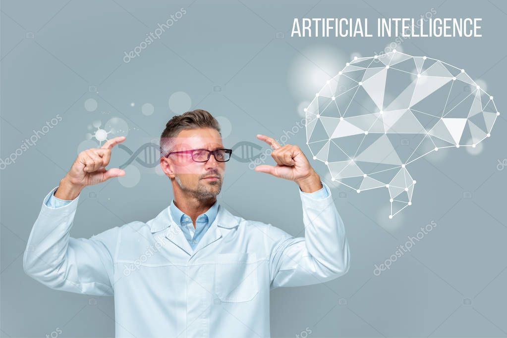 Handsome scientist in glasses holding medical interface with dna and brain isolated on grey, artificial intelligence concept