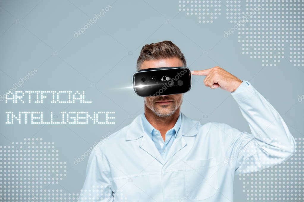 Scientist  in virtual reality headset pointing on his head isolated on grey, artificial intelligence concept
