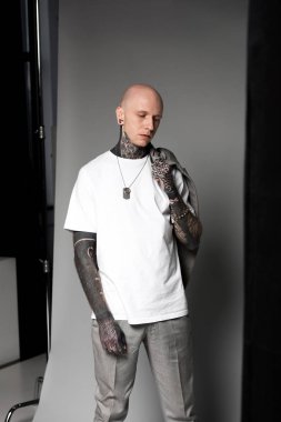 studio elbise omuz ve ayakta tutan dövmeli genç kel adam