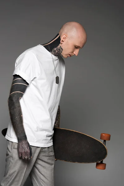 Vista Lateral Homem Tatuado Careca Shirt Branca Segurando Skate Olhando — Fotografia de Stock