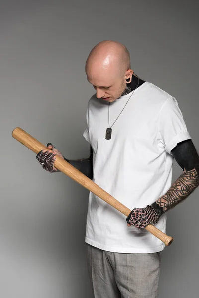 秃头纹身男子在白色 T恤拿着棒球棒在灰色 — 图库照片