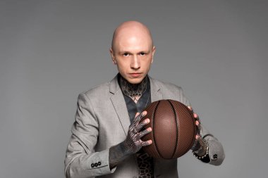 basketbol topu tutarak ve gri izole kamera bakarak elbiseli ciddi kel dövmeli adam 
