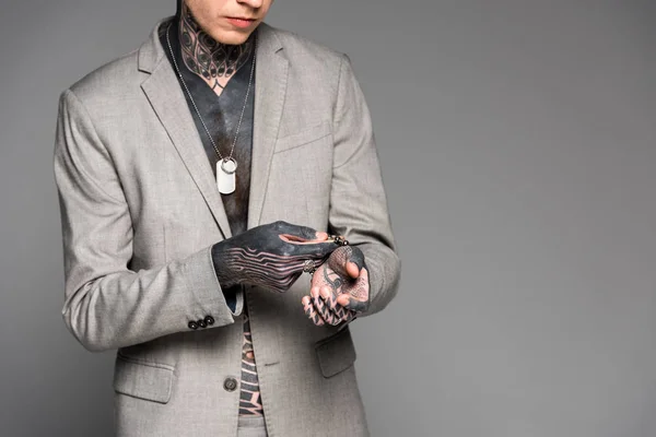 スタイリッシュな刺青の男グレーに分離されたブレスレットの調整のクロップ撮影 — ストック写真