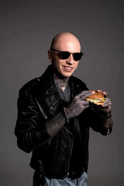 Tattooed Man Leather Jacket Sunglasses Holding Tasty Burger Smiling Camera — Stock Photo, Image