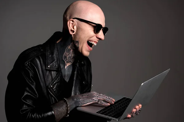 Careca Tatuado Homem Jaqueta Couro Óculos Sol Usando Laptop Rindo — Fotografia de Stock