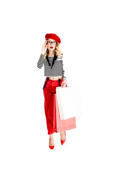 惊讶的女人在眼镜和红色贝雷帽拿着购物袋孤立在白色 — 图库照片