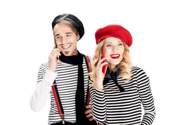 happy couple in berets talking on smartphones isolated on white 