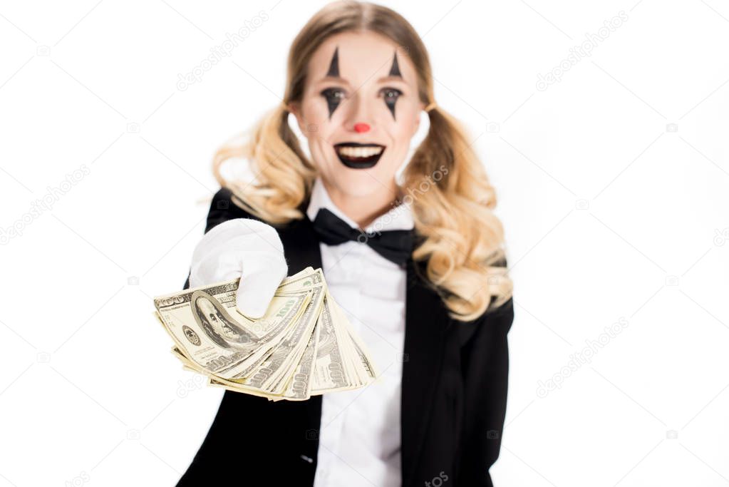 smiling clown with blonde hair holding dollar banknotes isolated on white 