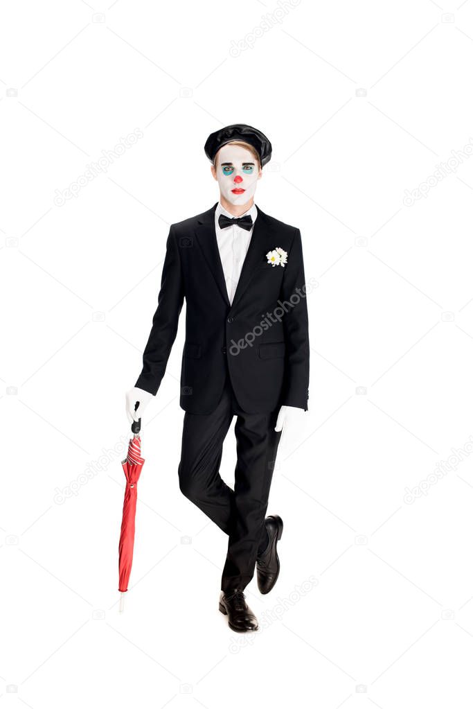 serious clown in suit and black beret holding umbrella while standing isolated on white 