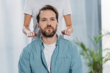 cropped shot of peaceful bearded man receiving healing reiki therapy clipart