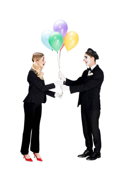cheerful clown giving balloons to woman in suit isolated on white 