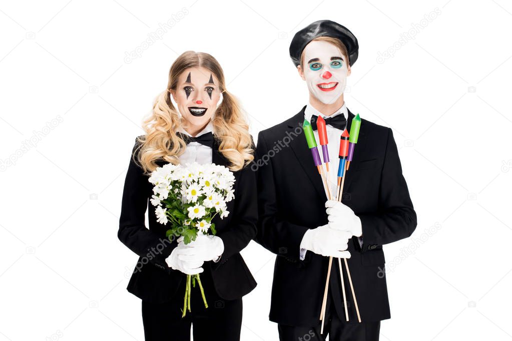 cheerful couple of clowns holding flowers and firecrackers in hands isolated on white 