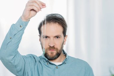 serious bearded male hypnotist holding dowsing and looking at camera  clipart