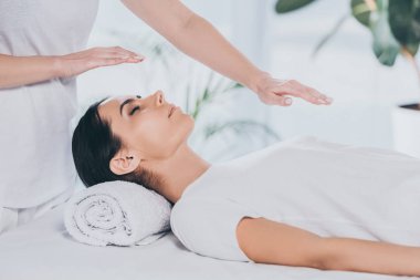 kapalı gözlerle baş ve göğüs üzerinde reiki tedavi gören genç kadın görüntüsünü kırpılmış