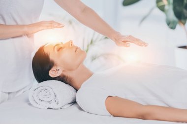 Genç kadın kapalı gözlerle sakinleştirmeye reiki şifacı terapi seansı yapıyor kadeh kırpılmış