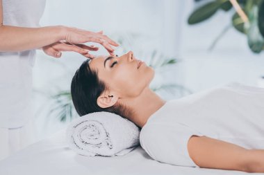 Genç kadın kapalı gözlerle sakinleştirmeye şifa terapi yapıyor reiki uzmanı kadeh kırpılmış