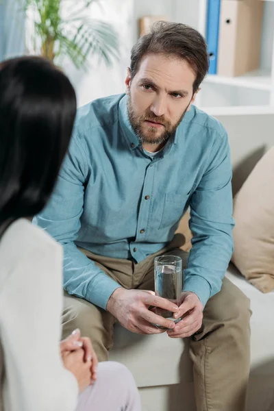 Tiro Recortado Hombre Barbudo Molesto Sosteniendo Vaso Agua Mirando Psicoterapeuta — Foto de Stock