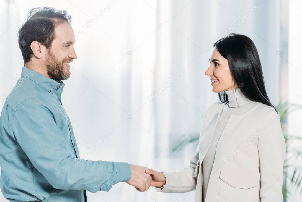 side view of psychotherapist and patient shaking hands and smiling each other