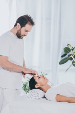 sakallı şifacı reiki tedavi oturum kapalı gözler ile genç kadın için yapıyor yan görünüm