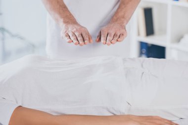 cropped shot of woman receiving reiki healing session above stomach clipart