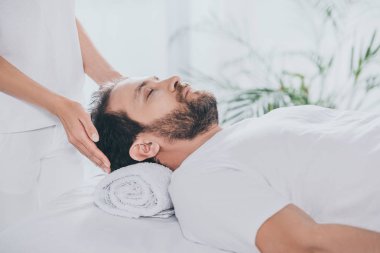 cropped shot of man with closed eyes receiving reiki treatment clipart